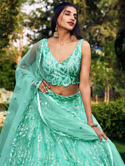 Woman wearing a green sequined outfit with a blurred natural background